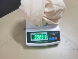 Detail view of the clothing fabric placed on an electronic digital scale for precise weight.