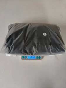 Packaging detail view of the folded dark top garment on a scale showing item weight.