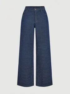 Closeup view of the woven pattern, high waist design and button details on denim pants.