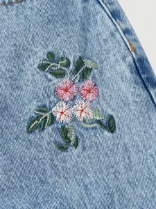 Close-up detail of stylish embroidered floral denim jeans fabric with premium stitching.