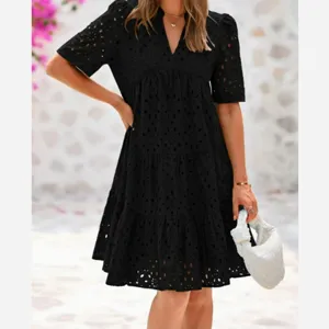 Detailed view of the elegant black eyelet embroidered dress, showcasing the V-neck and tiered style.