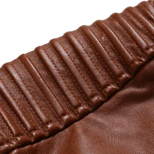 Gros plan détail d'une veste de moto en cuir PU marron pour homme avec texture matelassée.