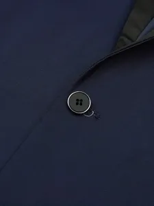 Close-up detail shot of a classic navy blue men suit jacket, highlighting lapel and button texture.