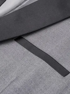 Detail shot of men's grey suit jacket featuring shawl lapel and pocket close-up.