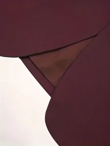 Close-up detail of men's burgundy suit jacket fabric, showcasing lapel texture and inner lining.