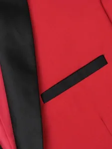 Close-up detail of men's red tuxedo blazer showing black satin lapel and pocket trim.