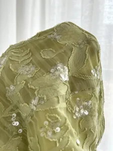 Detail of light green textured strapless top with sparkling sequin embroidery for summer style.