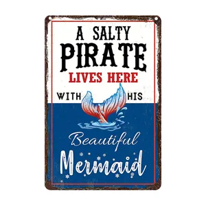 Closeup detail of vintage ocean style metal wall sign featuring mermaid tail graphic and text.