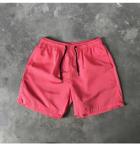 Detailaufnahme von rosa Herren Badeshorts mit schwarzem Kordelzug und softem Stoff.