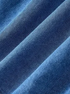 Blue denim fabric detail texture showing soft diagonal folds and high quality material.