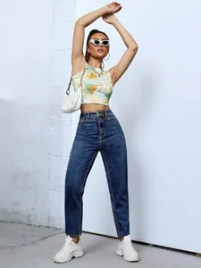 Stylish women's high-waisted tapered denim jeans paired with an abstract print crop top.