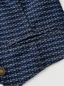 Detailed view of women's dark blue denim fabric with orange contrast stitching and button.