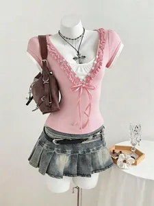 Dettaglio del set di vestiti con top corto a volant rosa e gonna plissettata.