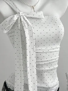 Close-up detail of the elegant white top featuring classic black polka dots and a large bow.