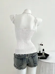 Vista dettagliata di un elegante top bianco smockato con spalline delicate e vestibilità slim.