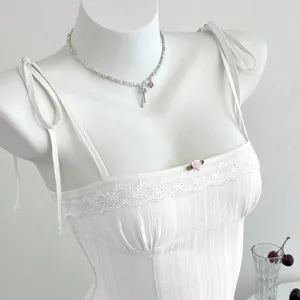 Dettaglio canotta bianca con bordo in pizzo, spalline e graziosa decorazione con rosa rosa.