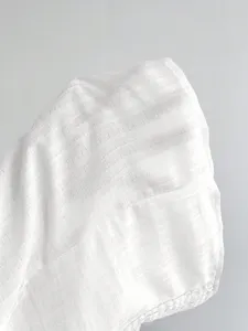 Primo piano della texture del tessuto della canotta da donna bianca e dettaglio in pizzo.