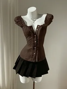 Detail showcase of the elegant brown puff sleeve blouse with ruffle trim and button front.