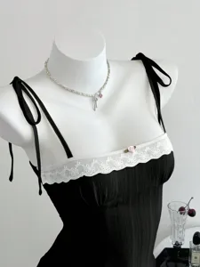 Primo piano di canotta estiva nera da donna con bordo in pizzo bianco e decoro di rosa.