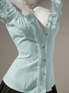 Close-up of light blue women's short sleeve shirt, featuring ruffles and metallic snap buttons.