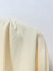 Primo piano dettaglio di texture tessuto t-shirt in maglia e drappeggio spalla da donna.
