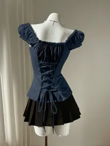 Back view of a chic navy blue puff sleeve blouse with lace-up back design and black skirt.