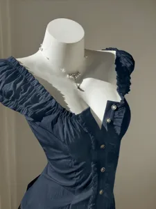Detailed view of the dark blue sweet puff sleeve blouse with pearl necklace accessorized.
