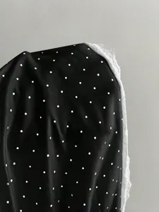 Black polka dot camisole detail with white lace trim, stylish sweet design for women's apparel.