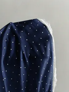 Detailed view of the dark blue polka dot fabric with delicate white lace trim for women's apparel.