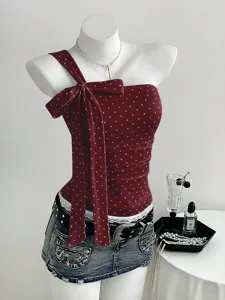 Detail view of the wine red polka dot one-shoulder bow camisole paired with a chic denim skirt.