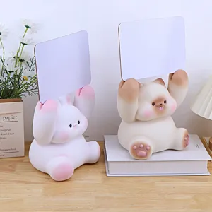 Cute animal piggy bank detail, resin rabbit and cat holding message boards on wooden desk.