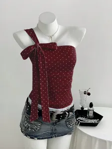 Detailed view of dark red polkadot one-shoulder top with elegant bow and chic denim skirt.
