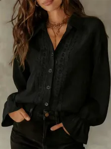 Primo piano dell'elegante camicia nera a maniche lunghe con dettagli in pizzo sul davanti.