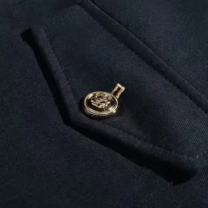Primer plano de chaqueta casual con botón metálico dorado texturizado y bolsillo con solapa.