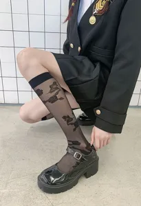 Detailed view of sheer black mid-tube socks with pattern, paired with classic Mary Jane shoes.