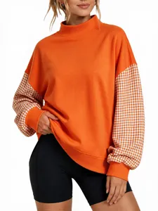 Detail view of the orange mock neck sweatshirt featuring stylish plaid long sleeves.