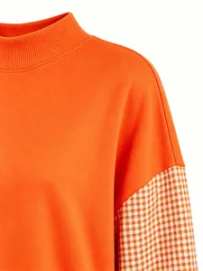 Orange mock neck sweatshirt detail featuring plaid spliced long sleeves and soft cotton fabric.