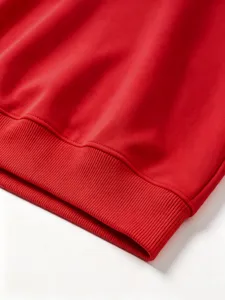 Close up of red sweatshirt ribbed hem detail, solid color casual top knit fabric texture.