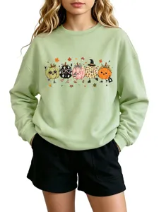 Detail shot of a light green crewneck sweatshirt featuring a cute 5-pumpkin autumn cartoon graphic.