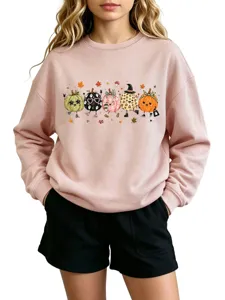 Close-up detail of the cute autumn pumpkin graphic print on the soft pink crewneck sweatshirt.