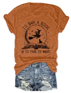 Detailed view of an orange short sleeve t-shirt featuring a witch book graphic, paired with denim.