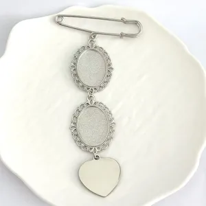 Close-up of silver oval bezel brooch base with heart charm on white dish for DIY jewelry crafting.