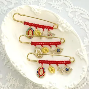 Detailed shot of red rope woven rhinestone brooch with evil eye cross and Mary charms pin.
