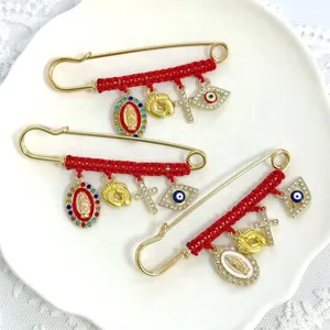 Detailed shot of red string woven rhinestone brooch safety pins with evil eye and cross charms