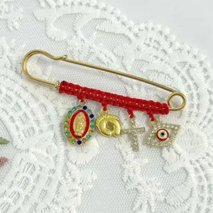Close-up of red woven rope brooch featuring evil eye, cross and religious charms with rhinestones.