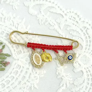 Detailed view of the red braided rhinestone brooch featuring evil eye and cross charms.