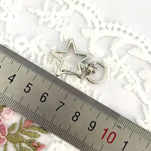 Close up detail view of star shaped metal keychain lobster clasp with size ruler.