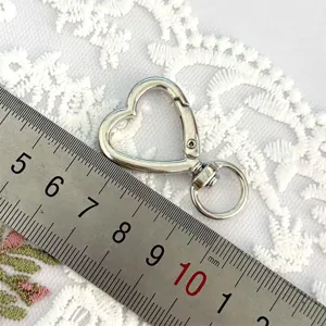 Detailed view of silver heart-shaped alloy keychain snap hook with swivel ring for crafts DIY.
