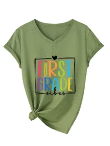 Détail de t-shirt vert à col en V et manches courtes avec imprimé coloré first grade vibes et nœud.