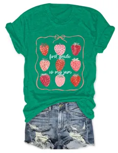 T-shirt vert en coton avec imprimé graphique de fraises et détail de lettres.